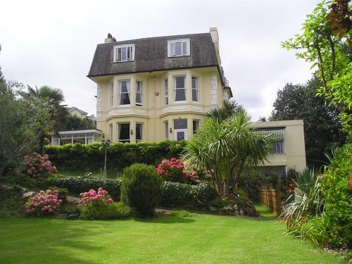 a large yellow house with a green yard at The Elmington Hotel in Torquay