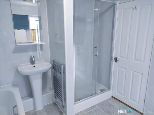 a white bathroom with a shower and a sink at Station Cottage - Gorgeous property with breathtaking views of Neyland Waterway in Neyland