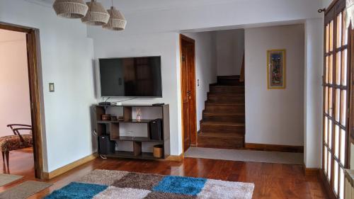 a living room with a television and a staircase at Hostel Sauce in Mar del Plata
