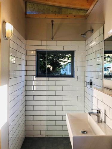 a white tiled bathroom with a sink and a window at Palm and Pine Cottage in Cape Town