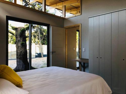 a bedroom with a large bed and a window at Palm and Pine Cottage in Cape Town