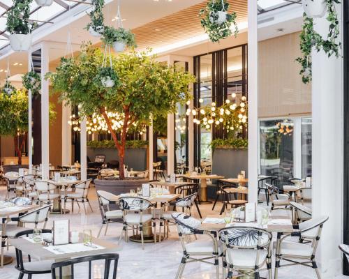 an empty restaurant with tables and chairs and trees at Sofitel Dubai The Obelisk in Dubai