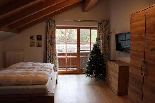 a bedroom with a christmas tree and a large window at Ferienwohnung Pferdehof Pankratz in Iffeldorf