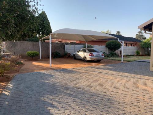 a car parked under a large umbrella in a driveway at Happy Living Guesthouse in Vereeniging