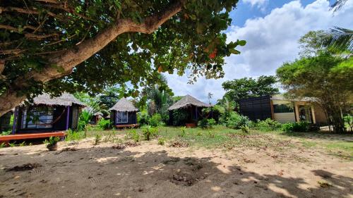 a group of huts in a yard with a tree at Monkey Island Resort Koh Mak in Ko Mak