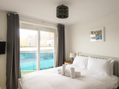 a bedroom with a white bed and a large window at Nautical Breeze in Weymouth