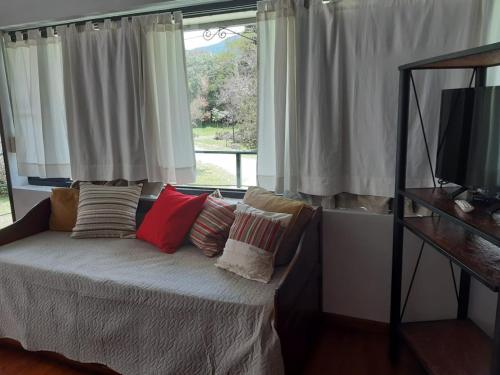 a bedroom with a bed with pillows and a window at Nuevas Cabañas Del Sol in San Lorenzo