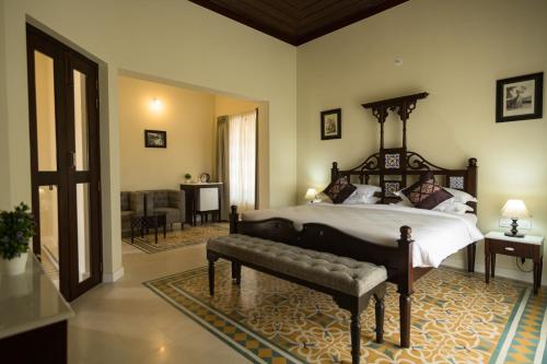 a bedroom with a large bed with a bench in it at The Foothills - A Boutique Hotel in Siolim