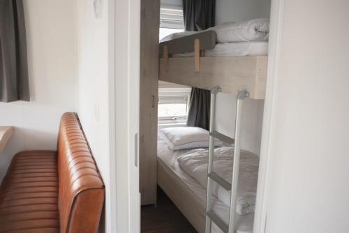 two bunk beds in a small room with a couch at 6-persoons Veluwelodge XL in Voorthuizen