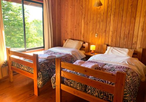 two beds in a room with a window at Mirador Los Volcanes Lodge & Boutique in Pucón