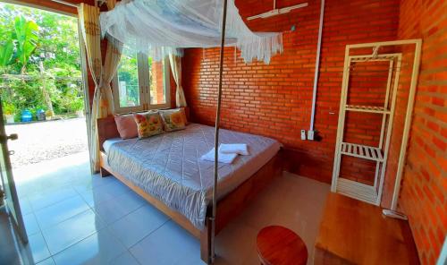 sypialnia z łóżkiem z baldachimem w ceglanej ścianie w obiekcie Cat Tien Backpackers Hostel w mieście Cat Tien