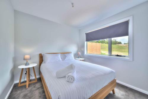 biała sypialnia z łóżkiem i oknem w obiekcie Archella 2 w mieście Coles Bay