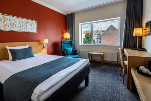 um quarto de hotel com uma cama, uma secretária e uma janela em Scandic Aalborg City em Aalborg