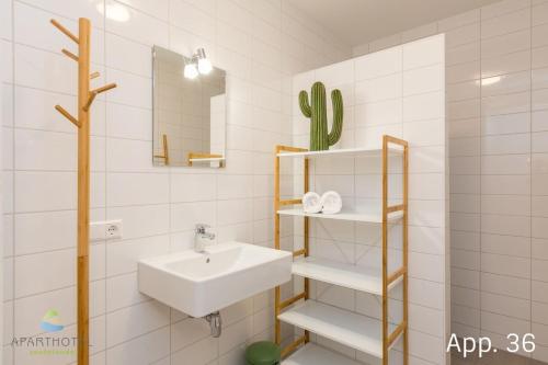 ein weißes Badezimmer mit einem Waschbecken und einem Spiegel in der Unterkunft 3-persoons comfort appartement in Zoutelande