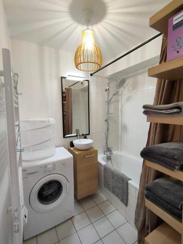 une salle de bain avec une machine à laver et un lavabo dans l'établissement jeu de paume, à Bayonne