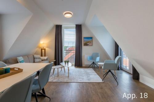 uma sala de estar com um sofá, uma mesa e cadeiras em Luxe 6-persoons appartement em Zoutelande