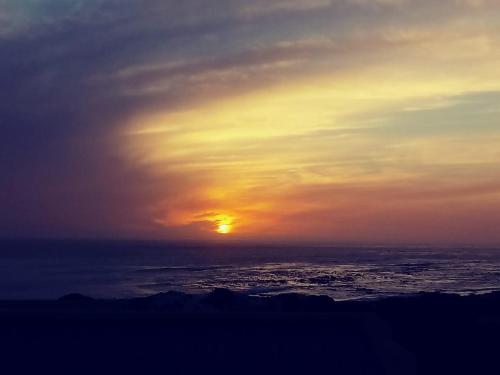 a sunset over the ocean with the sun in the sky at Sandy Feet Self Catering Accommodation in Pearly Beach