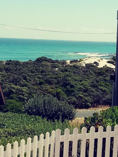 a white picket fence with a view of the ocean at Sandy Feet Self Catering Accommodation in Pearly Beach