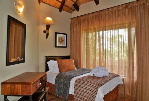 a bedroom with a bed and a window at BushTime Mabula in Mabula