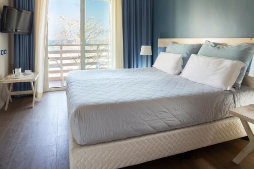 a bedroom with a large white bed with a balcony at Hotel LaMorosa in Rimini