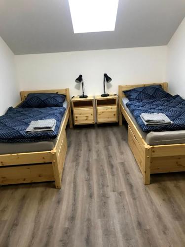 2 łóżka pojedyncze w pokoju z drewnianą podłogą w obiekcie Ubytování Osové w mieście Velké Meziříčí