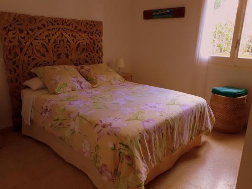 a bedroom with a bed with a floral bedspread and a window at Roses sobre el Mar in Roses