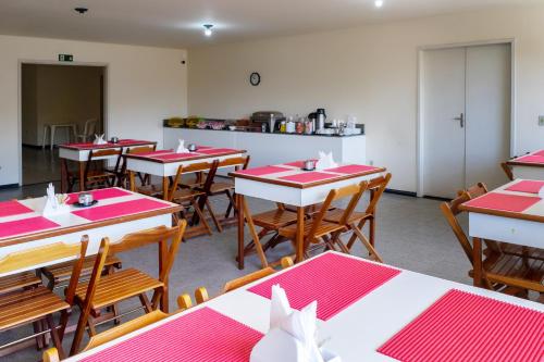 comedor con mesas rojas y sillas de madera en Piúma Palace Hotel, en Piúma