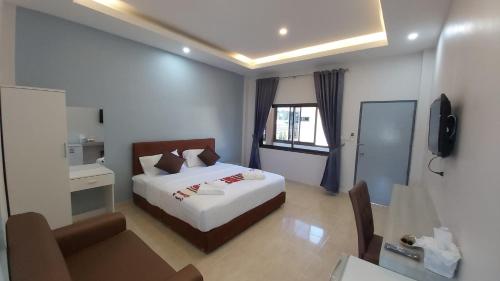 a bedroom with a bed and a desk and a television at New blessing Home นิวเบลสซิ่ง โฮม in Nan