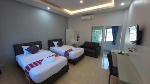 una habitación de hotel con 2 camas y una silla en แดยอน โฮม(Daeyeon Home), en Nan