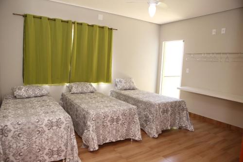 a room with two beds and a green curtain at Pousada Pérola Mineira in Piauí