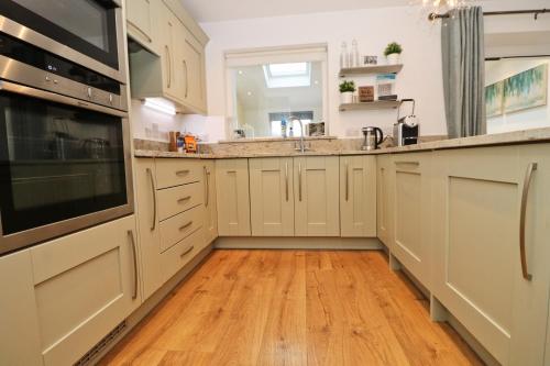 
a kitchen with a stove, sink and cabinets at NEAR BEACHES, contemporary home in village centre in Saint Merryn
