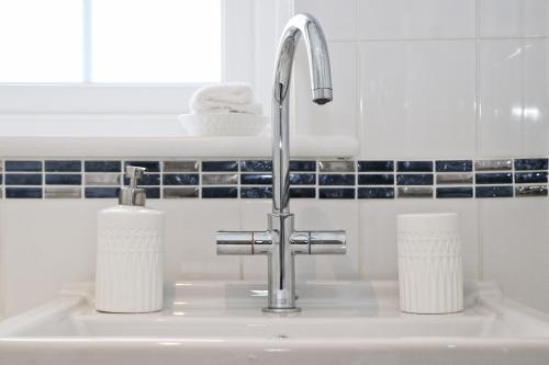 a sink with two paper towels and a faucet at NEAR BEACHES, contemporary home in village centre in St Merryn