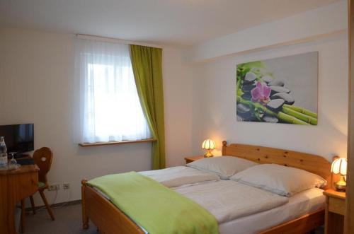 a bedroom with a bed with a green blanket on it at Hotel Gasthaus Zur Linde in Glottertal