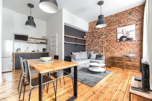 ein Wohnzimmer mit einem Tisch und einer Ziegelwand in der Unterkunft Apartament Absynth in Stettin