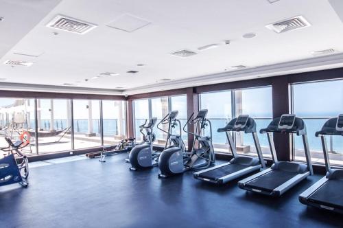 een fitnessruimte met cardio-apparatuur in een gebouw met ramen bij 2 Bedroom Deluxe Beach Apartment Al Marjan in Ras al Khaimah