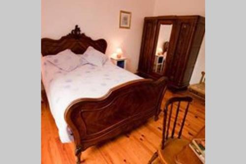 a large wooden bed in a bedroom with a mirror at Coeur De Combray, in Ernes