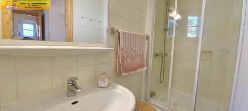 a white bathroom with a sink and a shower at Ferienhaus Almrausch by FiS - Fun in Styria in Tauplitz