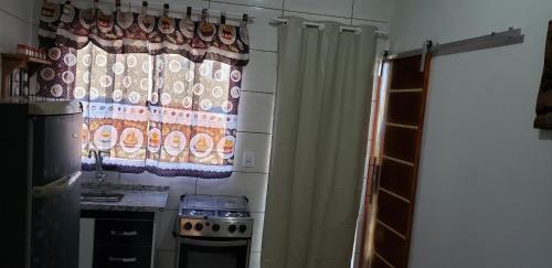 - une cuisine avec un rideau de douche et une cuisinière dans l'établissement Kitnet da Lú, à São Thomé das Letras