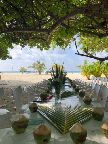 a table on a beach with chairs and a table with a tableablish at Huvan Inn in Fulidhoo