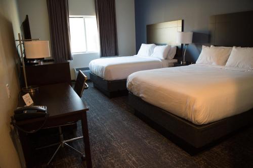 a hotel room with two beds and a table at Cobblestone Inn & Suites - Forest City in Forest City