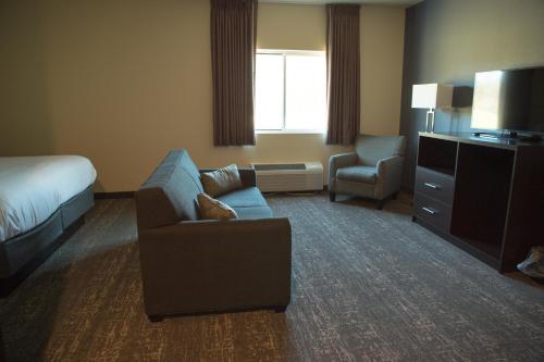 a hotel room with a couch and a bed and a chair at Cobblestone Inn & Suites - Forest City in Forest City