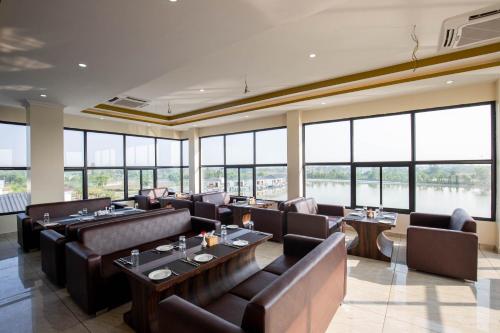 a restaurant with couches and tables and large windows at Lumbini Palace Resort in Lumbini