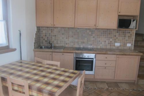 a kitchen with a table and a sink and a stove at Chalet Rin da Pemont in Livigno