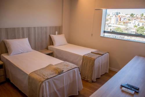 um quarto de hotel com duas camas e uma janela em Boa Vista Hotel em Oliveira
