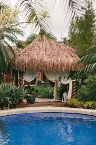 a resort with a straw hut with a swimming pool at Villa Bebek Hotel in Camburi