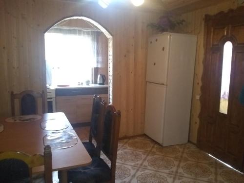 a kitchen with a table and a white refrigerator at Хатина в горах in Yablunytsya