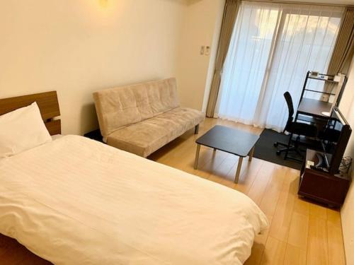 a bedroom with a bed and a chair and a table at Hamamoto Palace Taniyama - Vacation STAY 10397 in Kagoshima