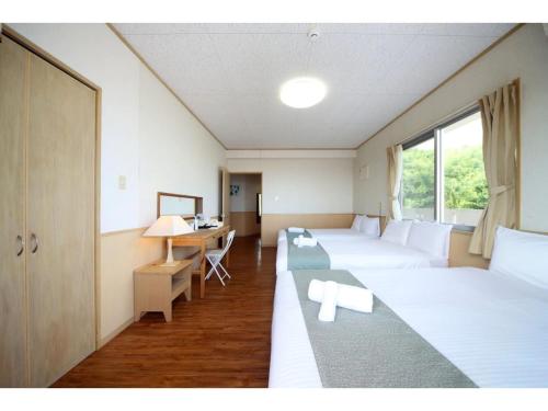Zimmer mit 2 Betten und einem Schreibtisch. in der Unterkunft Green Garden Hills 3F-1 - Vacation STAY 15233v in Okinawa