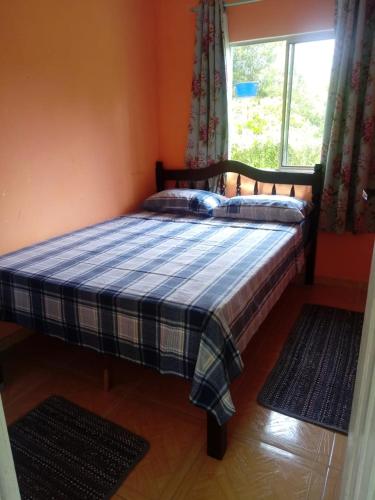 a bed in a room with a window and two rugs at Pousada Serena Superagui in Superagui