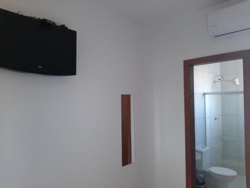 a bathroom with a toilet and a television on the wall at Pousada do caju in Serra